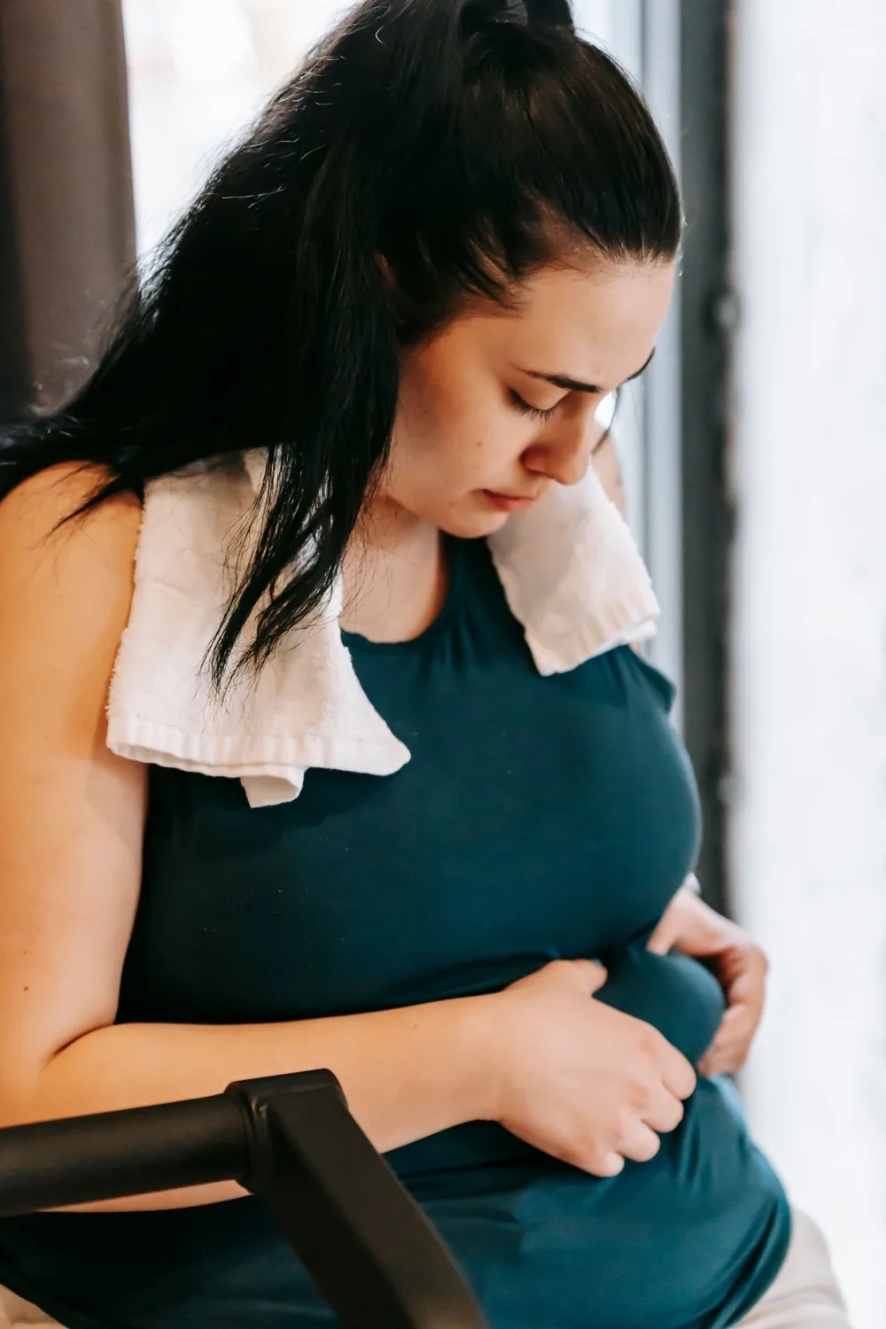 Vrouw in sportkleding die bezorgd naar haar buik kijkt